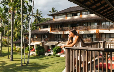 A man and a woman walking on a beach with palm trees