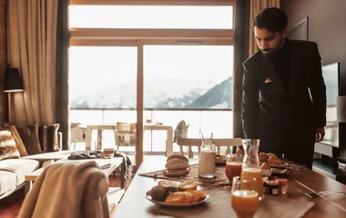 Majordome qui dresse le petit déjeuner dans un chalet à la montagne