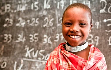 Enfant devant un tableau d'école lors d'un voyage au Kenya