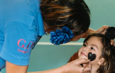 Mädchen wird von Kinderbetreuerin geschminkt