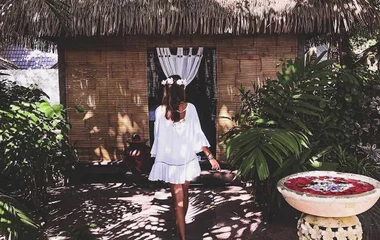 Eine Frau geht in eine tropische Hütte