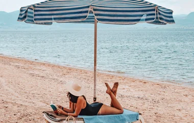 Frau unter einem Sonnenschirm am Strand