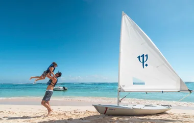 Vater mit Kind am Strand und Segelboot