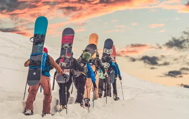Wanderer mit Snowboard auf dem Rücken im Schnee