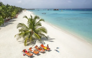Al sole su una delle bianchissime spiagge delle Maldive sotto le palme