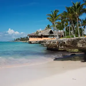 Spiaggia di sabbia bianca a Punta Cana con mare cristallino e palme tropicali al tramonto