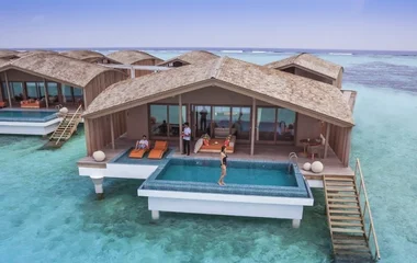 Spiaggia bianca alle Maldive con palme e mare turchese, meta ideale per una vacanza da sogno