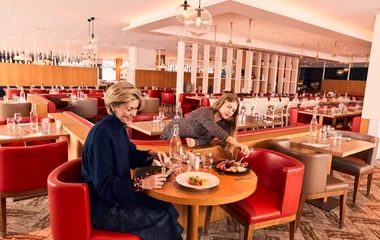 Duas pessoas sentadas em uma mesa apreciando a gastronomia alpina