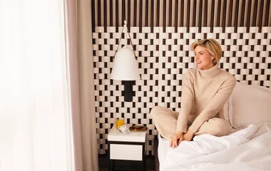 Mulher sorridente sentada na cama de um dos quartos de um resort Club Med All Inclusive.