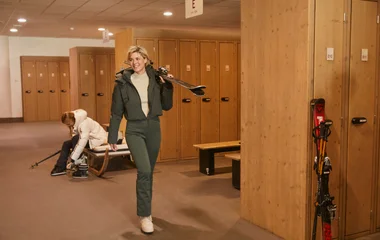 Uma mulher sorridente saindo da Ski Room com seu equipamento.