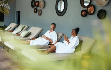 Un hombre y una mujer, en bata, sentados en sillas de spa.