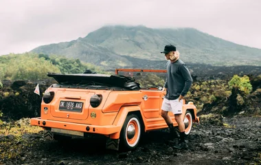 A person standing next to his jeep near Mount Batur