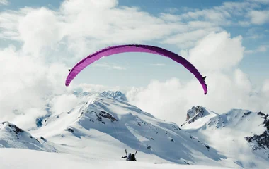 vista de uma montanha coberta de neve e uma pessoa no parapente