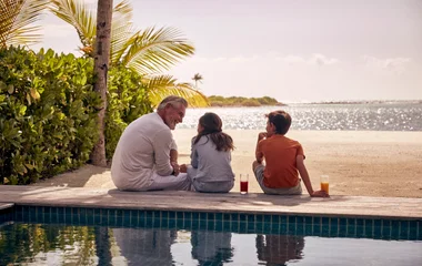 A man and 2 kids are having fun next to the pool in Maldives
