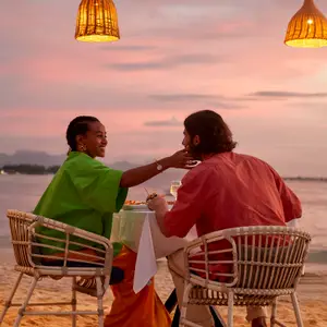 casal feliz sentados à mesa na praia