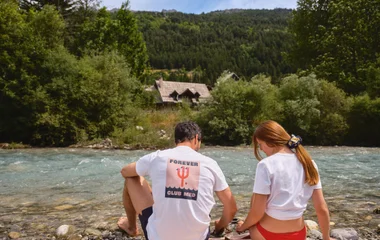 Casal a beira do rio com vista para as montanhas