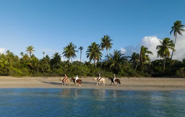 Gente montando a caballo en la playa.