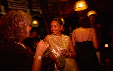 Mulher em uma festa conversando com outra hóspede.