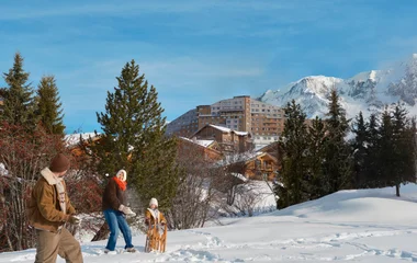 família feliz brincando na neve em frente ao resort Club Med