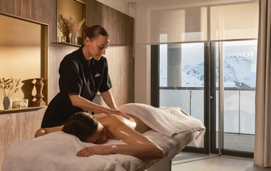 Mulher recebendo massage no spa com vista para as montanhas nevadas.