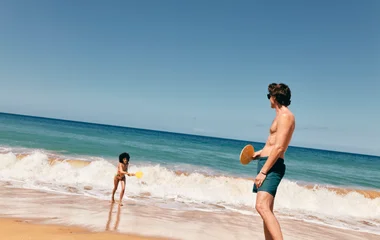 Casal jogando tenis na praia.