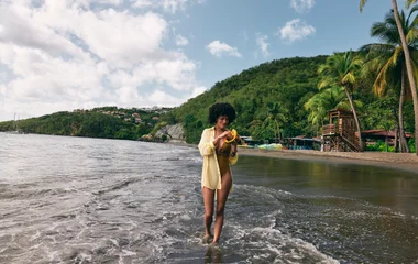 Mulher comendo enquanto caminha pela praia.