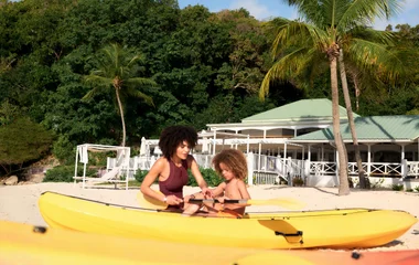 Niño y mujer mirando a los equipos de kayak.