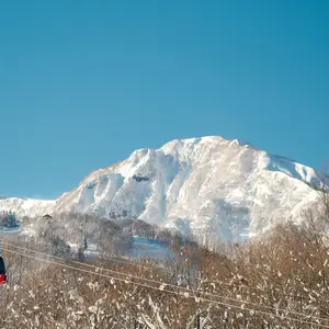A breathtaking view of a snowy mountain in Japan with a red cable car, perfect for winter travel.