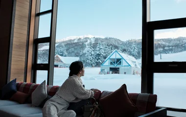 Woman looking at the snow through the window.