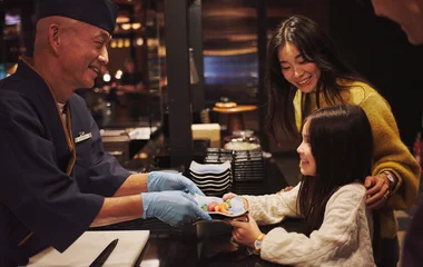 Little girl with her mom being served sushi by a chef at the Club Med Kiroro Grand Resort.