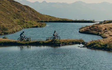 Dos personas andando en bicicleta cerca de un lago.