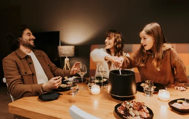 Padre, madre e hija cenando fondue.
